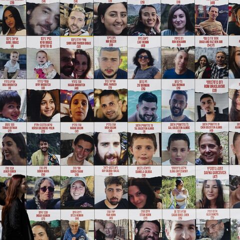 People pass by a building covered with photos of hostages who have been released or are still being held in the Gaza Strip, on March 26, 2024 in Tel Aviv, Israel.